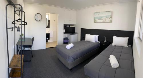 1 dormitorio con 2 camas, escritorio y reloj en The Seaview Tavern Motel, en Woolgoolga