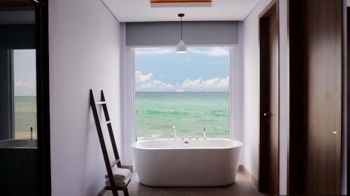 eine Badewanne im Bad mit einem großen Fenster in der Unterkunft One of A Kind Resort @Trikora Beach - Bintan 