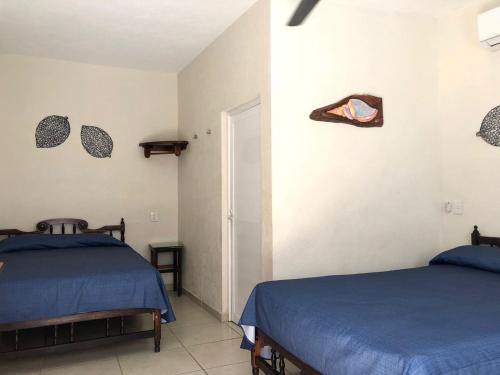 two beds in a bedroom with blue sheets at Bungalows Las Hamacas in San Patricio Melaque