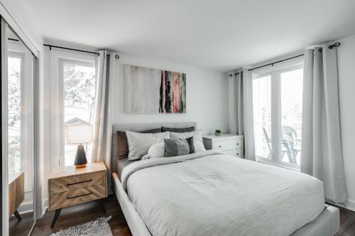 - une chambre blanche avec un lit et des fenêtres dans l'établissement Le Lightroom by Gestion ELITE, à Mont-Tremblant