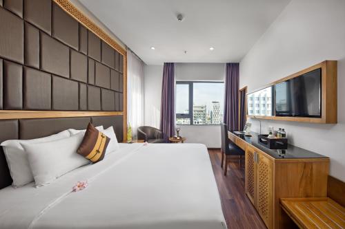 een slaapkamer met een bed, een bureau en een televisie bij Bliss Luxury Hotel & Spa in Da Nang
