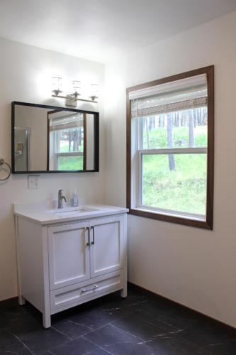 a bathroom with a sink and a mirror and a window at Cabin 2 at Horse Creek Resort in Rapid City