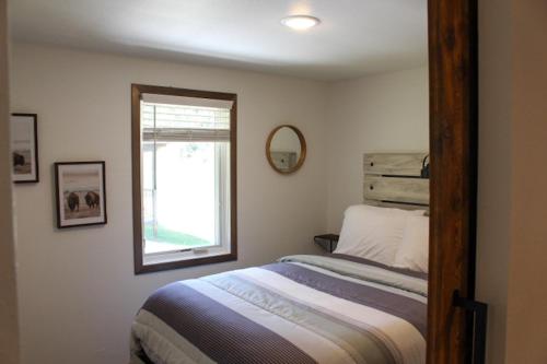 a bedroom with a bed with a mirror and a window at Cabin 2 at Horse Creek Resort in Rapid City