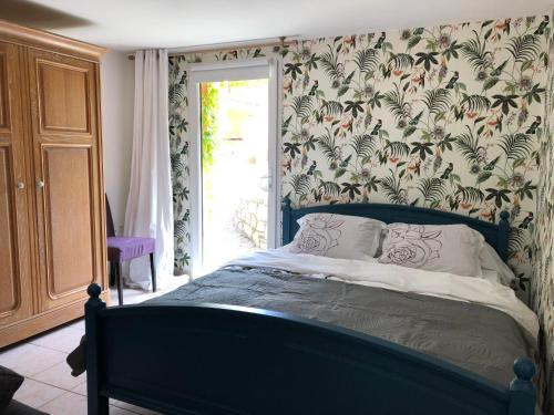 a bedroom with a blue bed with a floral wallpaper at Villa Catharina in Lorgues