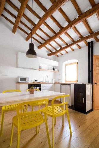 a kitchen with a yellow table and two yellow chairs at Ca lEspavil in Cardedeu
