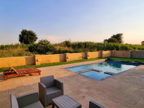 a patio with a pool and chairs and a bench at 391 Vaal de Grace Golf Estate, Parys in Parys