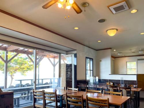 a restaurant with wooden tables and chairs and windows at Biwa-Lakeside Cottage B B Dylan in Minami-komatsu