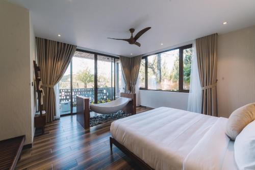 a bedroom with a bed and a chair and windows at Zen Valley Dalat in Da Lat