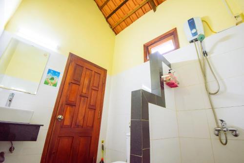 a bathroom with a shower and a toilet and a door at Kiki Coconut Beach Resort in Phu Quoc