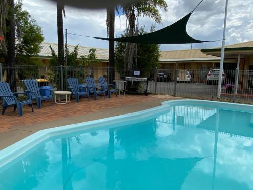 Miles的住宿－金西汽車旅館，一个带桌椅的游泳池和一个围栏