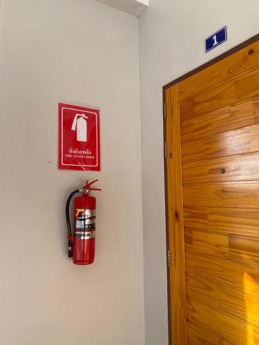 a fire extinguisher on a wall next to a door at โรงแรมคอมม่อนเวลธ์ Commonwealth Hotel&Resort in Suan Phung