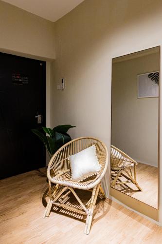 a wicker chair with a pillow sitting in front of a mirror at Urban Living Residence in Kuala Lumpur