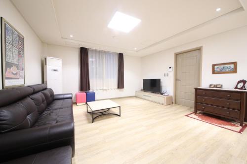 a living room with a black leather couch and a television at Moonbay Hotel in Busan