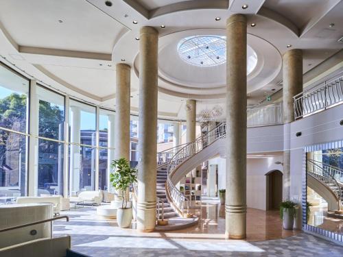 a large lobby with columns and a spiral staircase at Hotel Village Izukogen in Ito