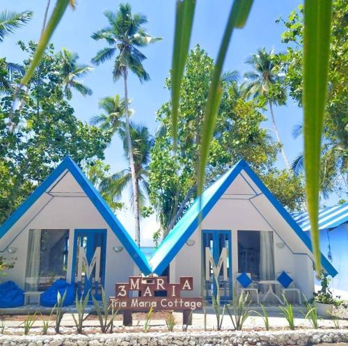 a building on the beach with palm trees in the background at Tria Maria Cottage in Ngurblut