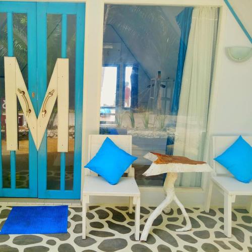 a room with two chairs and a door with the letter m at Tria Maria Cottage in Ngurblut
