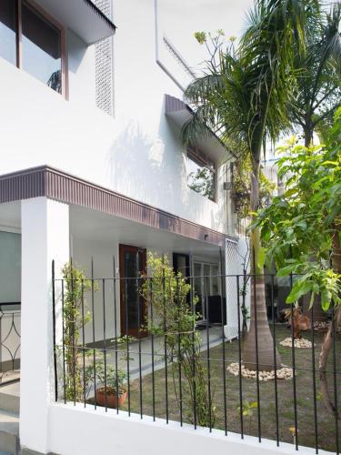 a white house with a fence and a palm tree at Frangipani Suite in New Delhi