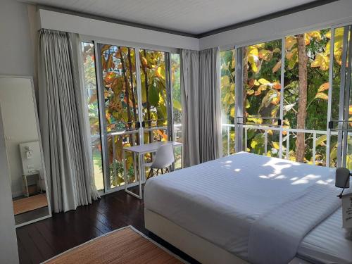 a bedroom with a bed and large windows at Cochet in Chiang Mai