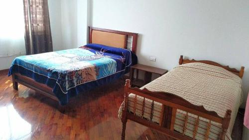 1 dormitorio con 2 camas y suelo de madera en Casas Danadri, Como En Casa en Riobamba