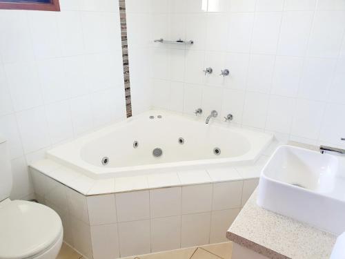 a white bathroom with a tub and a toilet at Werribee Park Motor Inn in Werribee