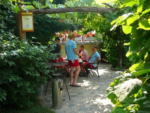 a group of people sitting at a table in a garden at Zöld sziget Apartmanház in Gyenesdiás