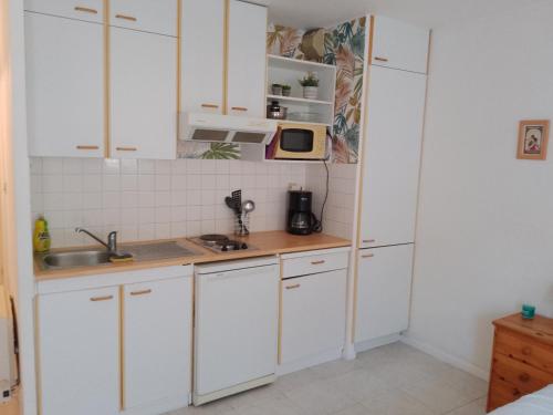 a kitchen with white cabinets and a microwave at Studio pour cure Eugénie les Bains in Eugénie-les-Bains
