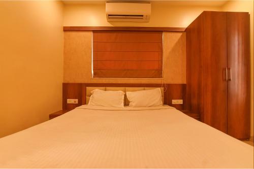 a bedroom with a white bed with a wooden headboard at Via Dream Plaza - Nr Biswa Bangla Gate in Kolkata
