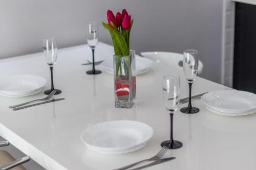 una mesa con platos y vasos y un jarrón con flores en Perlamar, en Calpe