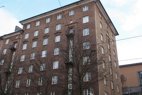 a large brick building with a tree in front of it at Kompakti Asunto Helsingin Sydämessä in Helsinki