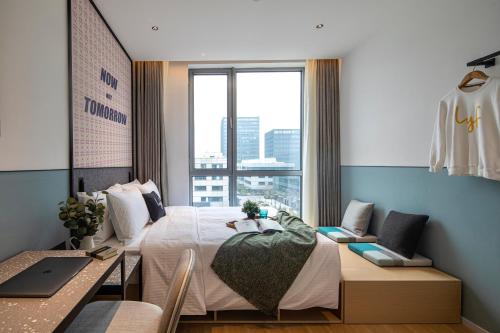 een slaapkamer met een bed, een bureau en een raam bij lyf by Ascott Hongqiao Shanghai NECC in Shanghai