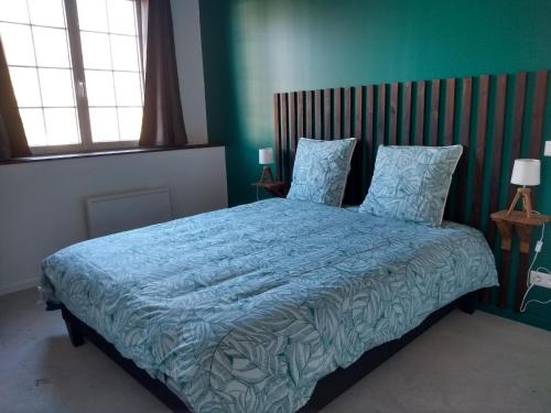 a bedroom with a bed with a blue comforter and two windows at l'airial in Souprosse