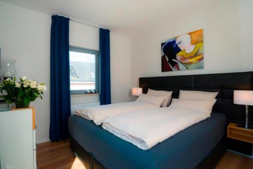 Schlafzimmer mit einem Bett mit blauen und weißen Kissen in der Unterkunft Ostsee - Maisonette - Appartement Nr 54 "Marina-Blick" im Strand Resort in Heiligenhafen