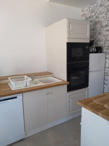 a kitchen with white cabinets and a sink and appliances at l'airial in Souprosse
