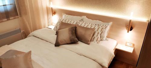 - une chambre avec un lit blanc et des oreillers dans l'établissement Apartment Bubica Zlatibor, à Zlatibor