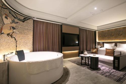 a hotel room with a bath tub and a bed at Qingdao Treasure Hotel in Qingdao