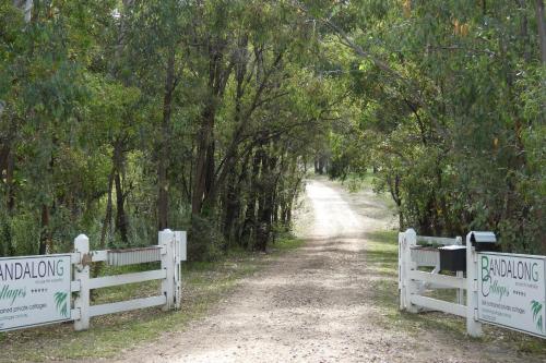 a dirt road with two fences and trees at Bandalong Cottages in Mudgee
