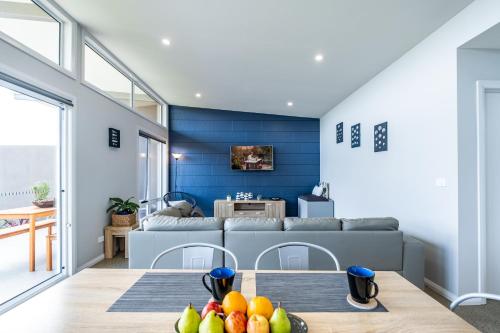 a living room with a couch and a table with fruit at Amaroo 1 - Freycinet Holiday Houses in Coles Bay