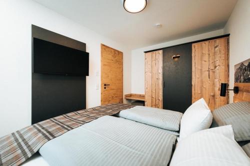 a bedroom with a bed and a couch and a tv at Living Mountain Tannheim in Tannheim