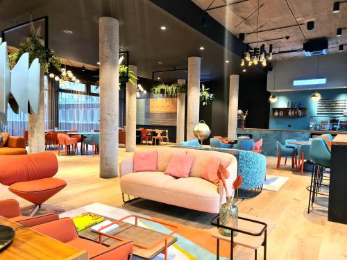 a lobby with a couch and tables and chairs at KONCEPT HOTEL International in Cologne