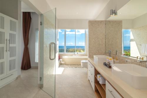 ein Badezimmer mit zwei Waschbecken, einer Badewanne und einer Dusche in der Unterkunft Villa IzaJay in Lovina