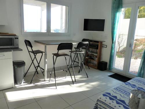 eine Küche mit einem Tisch mit 3 Stühlen und einem TV in der Unterkunft la belle bleue in Banyuls-sur-Mer