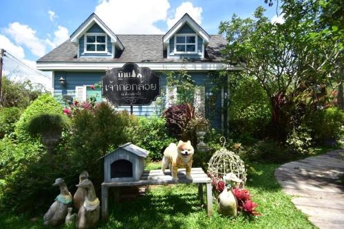 a dog statue sitting on a table in front of a house at Baan JaoKorKluay บ้านเจ้ากอกล้วย in Chiang Rai