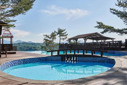 a swimming pool with a gazebo next to a lake at Club ES Jecheon Resort in Jecheon