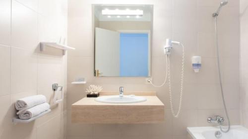 a bathroom with a sink and a mirror and a shower at Apartamentos Lemar in Colonia Sant Jordi