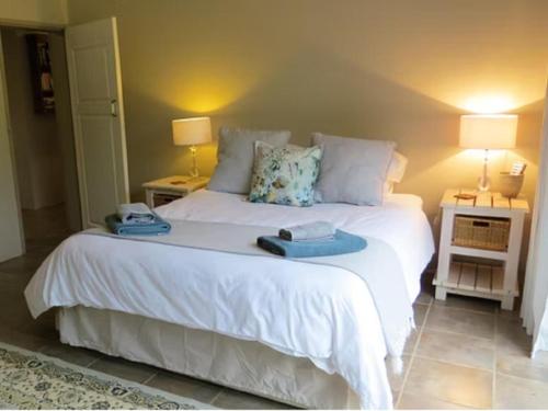 a bedroom with a large white bed with two night stands at East of East Guest Cottage in Avondzon