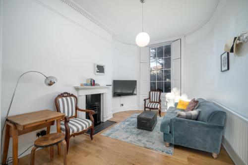 ein Wohnzimmer mit einem Sofa, Stühlen und einem TV in der Unterkunft JOIVY Modern 4 bed flat with communal courtyard in Angel, East London in London