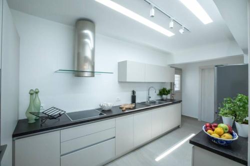 una cocina con armarios blancos y un bol de fruta en Villa Paraga, en Platis Gialos