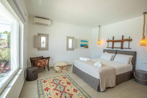 a bedroom with a bed and a chair and a window at Villa Paraga in Platis Yialos Mykonos