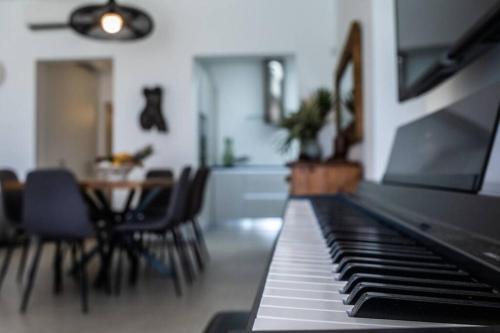 a piano in a living room with a table and chairs at Villa Paraga in Platis Yialos Mykonos