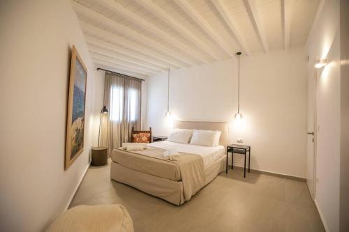 a large white bedroom with a bed and a table at Villa Paraga in Platis Yialos Mykonos